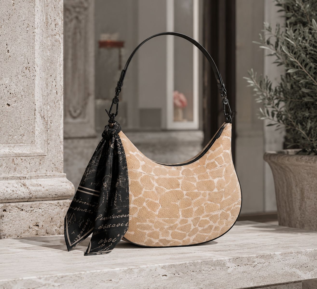 A Profundities leather shoulder bag with a printed silk scarf knotted to the strap, on travertine steps